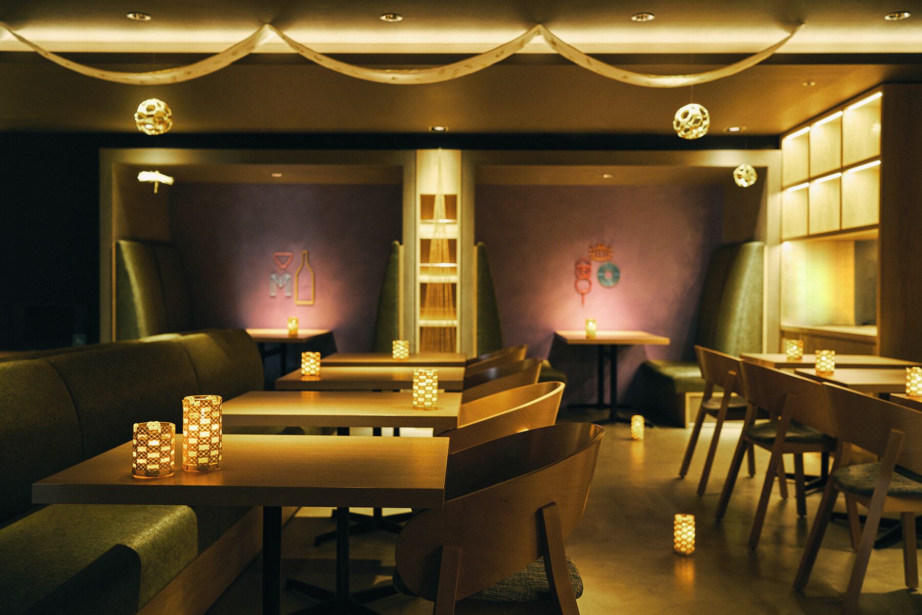 A restaurant with tables and chairs, warm lighting, and decorative elements on the walls.