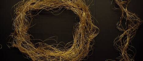 A tangled golden wire sculpture against a dark background.