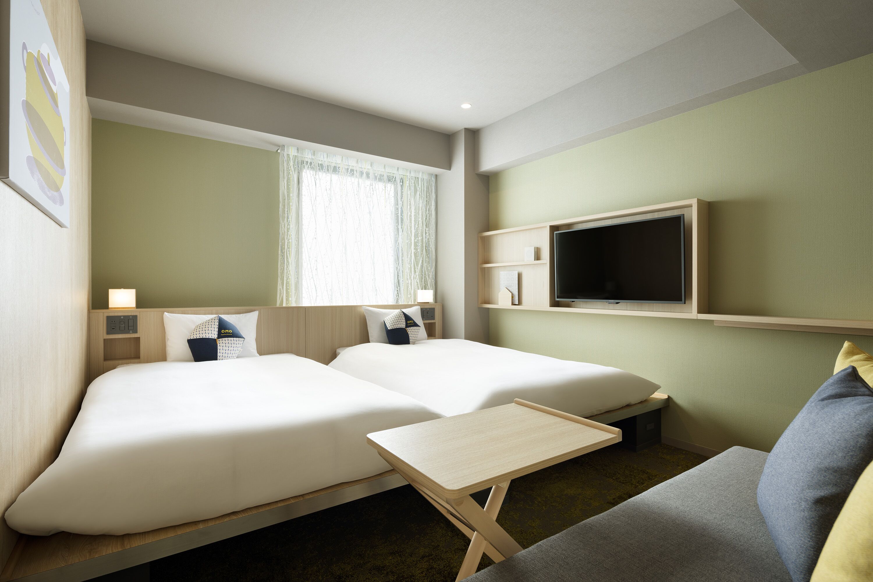 Habitació d'hotel amb dos llits, un televisor penjat a la paret i una taula petita.