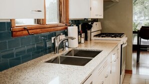 A kitchen with white cabinets, a granite countertop, a sink, and a window with a wooden frame. - Relax & Recharge: Mid-Century Modern Home with Sauna in Spring Green (Spring Green)