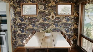 A dining area with a wooden table and chairs, patterned wallpaper, and a chandelier. - Relax & Recharge: Mid-Century Modern Home with Sauna in Spring Green (Spring Green)