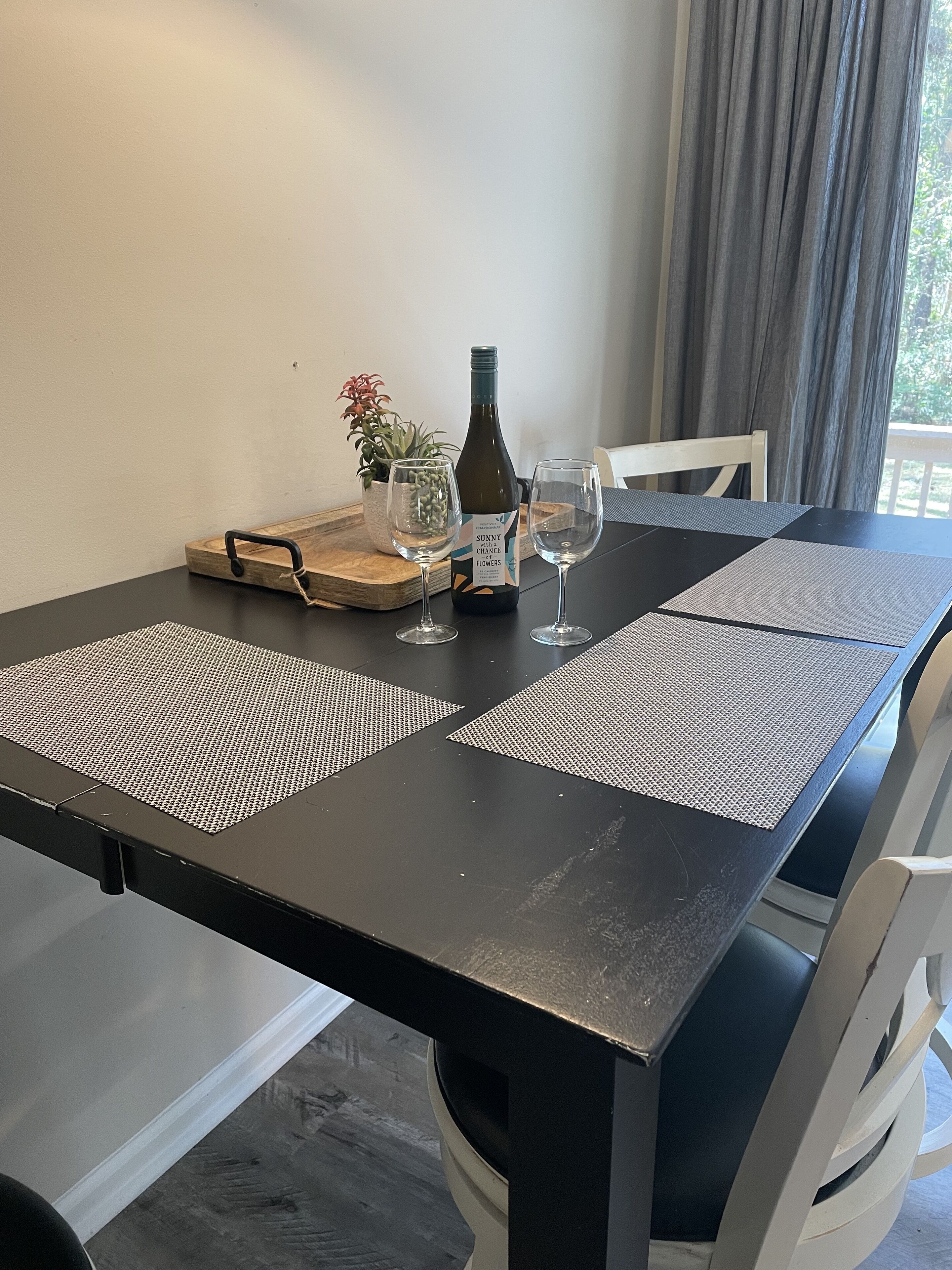 A dining table with a bottle of wine, two glasses, and a tray with a plant.