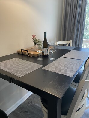 Una mesa de comedor con una botella de vino, dos copas, una bandeja con una planta y un mantel individual.