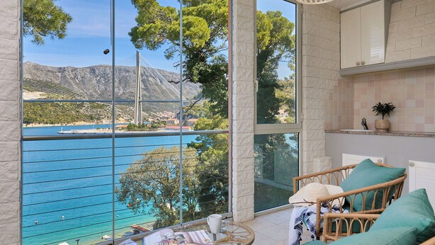 A balcony with a view of a coastal area, a wicker chair, and a table with a magazine. - Hedera Estate, Hedera A3 (Dubrovnik)