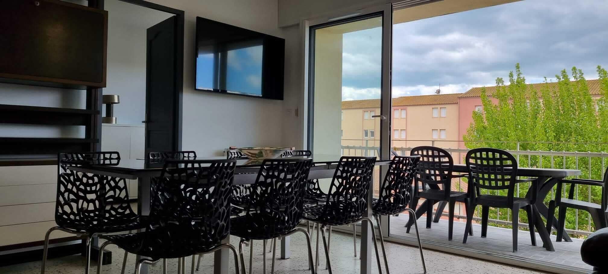 A balcony with outdoor seating and a view of buildings and trees.