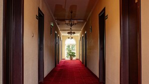 Ein Hotelgang mit rotem Teppich, Holztüren und einem Chandelier.