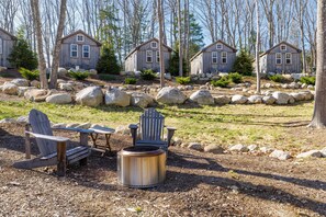 Uma área de cabanas com cadeiras Adirondack, uma fogueira e um caminho de pedra.
