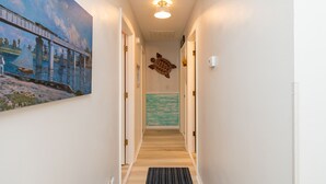 Un couloir orné d’un tableau représentant un pont et une tortue, avec un plancher en bois et un luminaire au plafond.