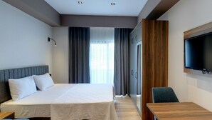 A hotel room with a bed, a TV mounted on the wall, a desk, and a chair. - Gorukle Alpas Yasam Hotel (Bursa)