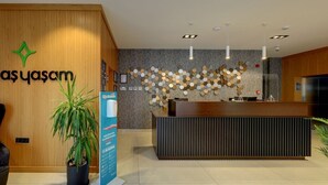 A reception area with a wooden reception desk, a sign for 'alpaş yasam', and a decorative wall with hexagonal mirrors. - Gorukle Alpas Yasam Hotel (Bursa)