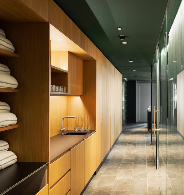 A modern kitchen with wooden cabinetry, a stainless steel sink, and a glass door leading to another room. - Hotel Galántha (Eisenstadt)