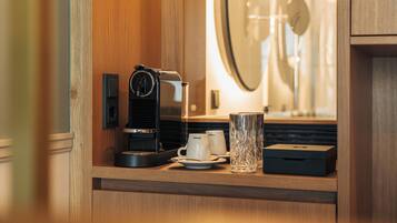 A coffee machine on a wooden counter with two white cups and a glass.