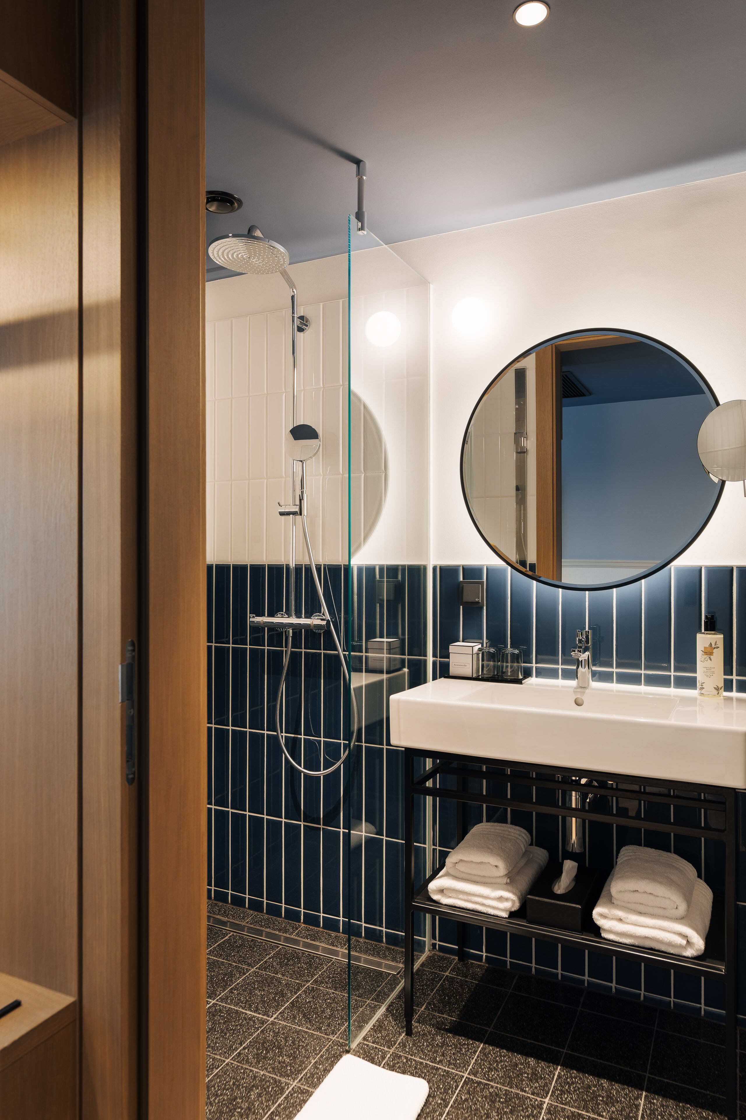 A modern bathroom with a shower, a sink with a mirror, and a towel rack.