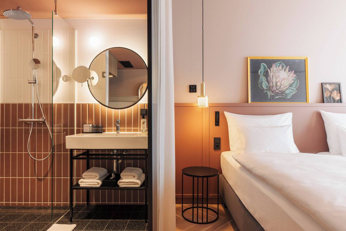 Un baño moderno con cabina de ducha de vidrio, un espejo redondo y un lavabo con toallero.