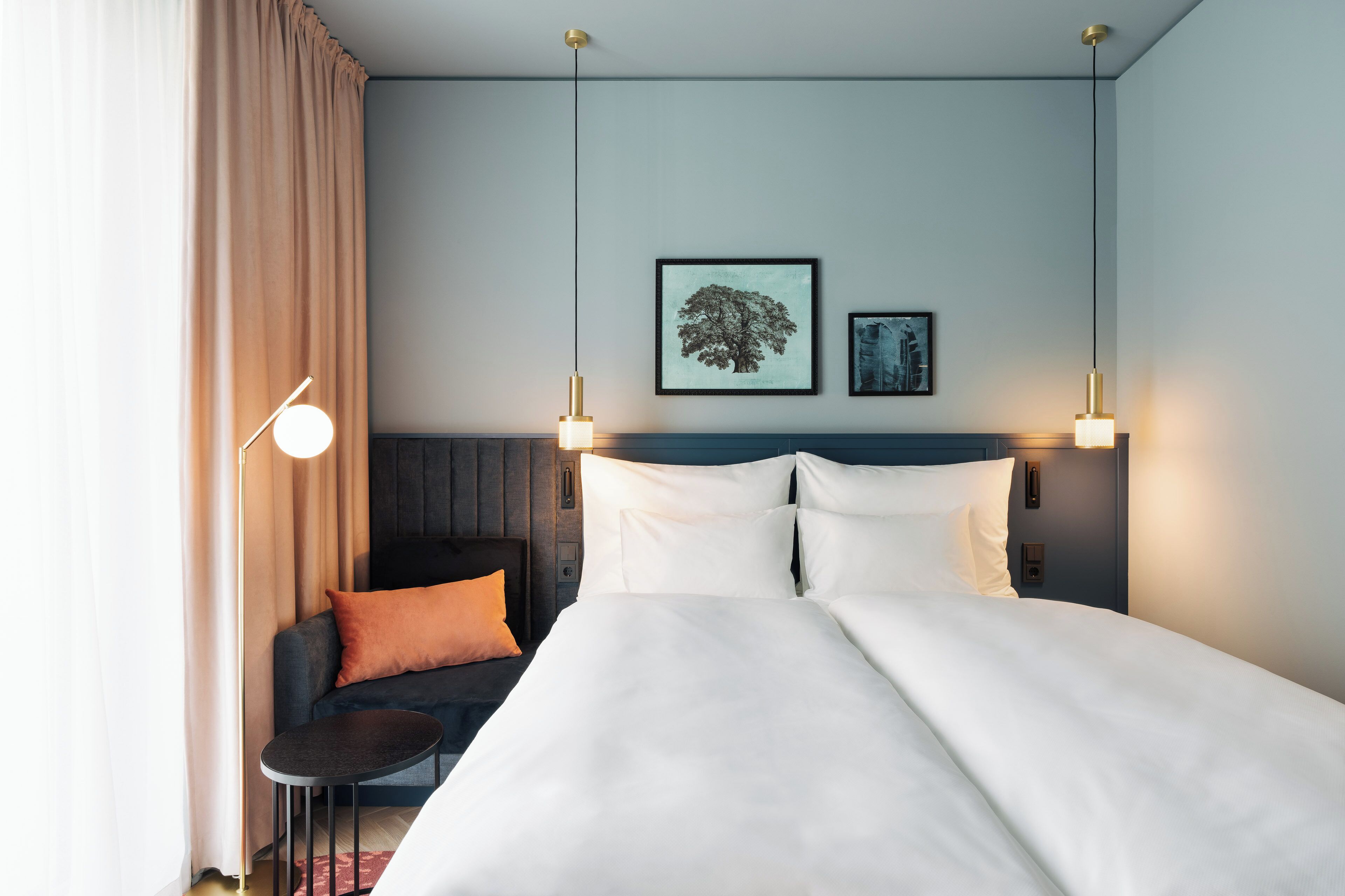 Een hotelkamer met een groot bed, een kleintje tafeltje, een bank en twee wandlampen.