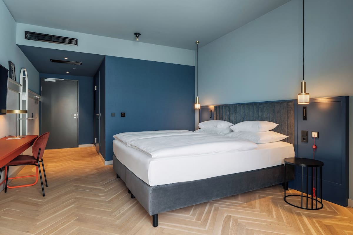 Una habitación de hotel moderna con una cama grande, un escritorio y una silla.