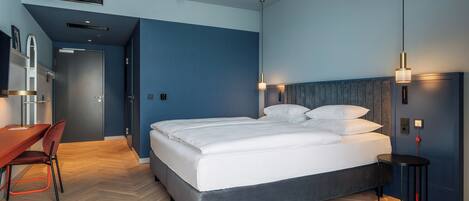 Une chambre d’hôtel moderne, dotée d’un grand lit, d’un bureau et d’une chaise.