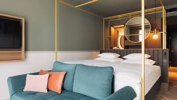 Una habitación de hotel moderna con cama, sofá, espejo grande y estructura de techo de madera.