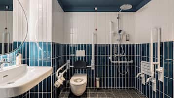 Ein Badezimmer mit weißem Waschbecken, Toilette, Dusche und Handlauf.