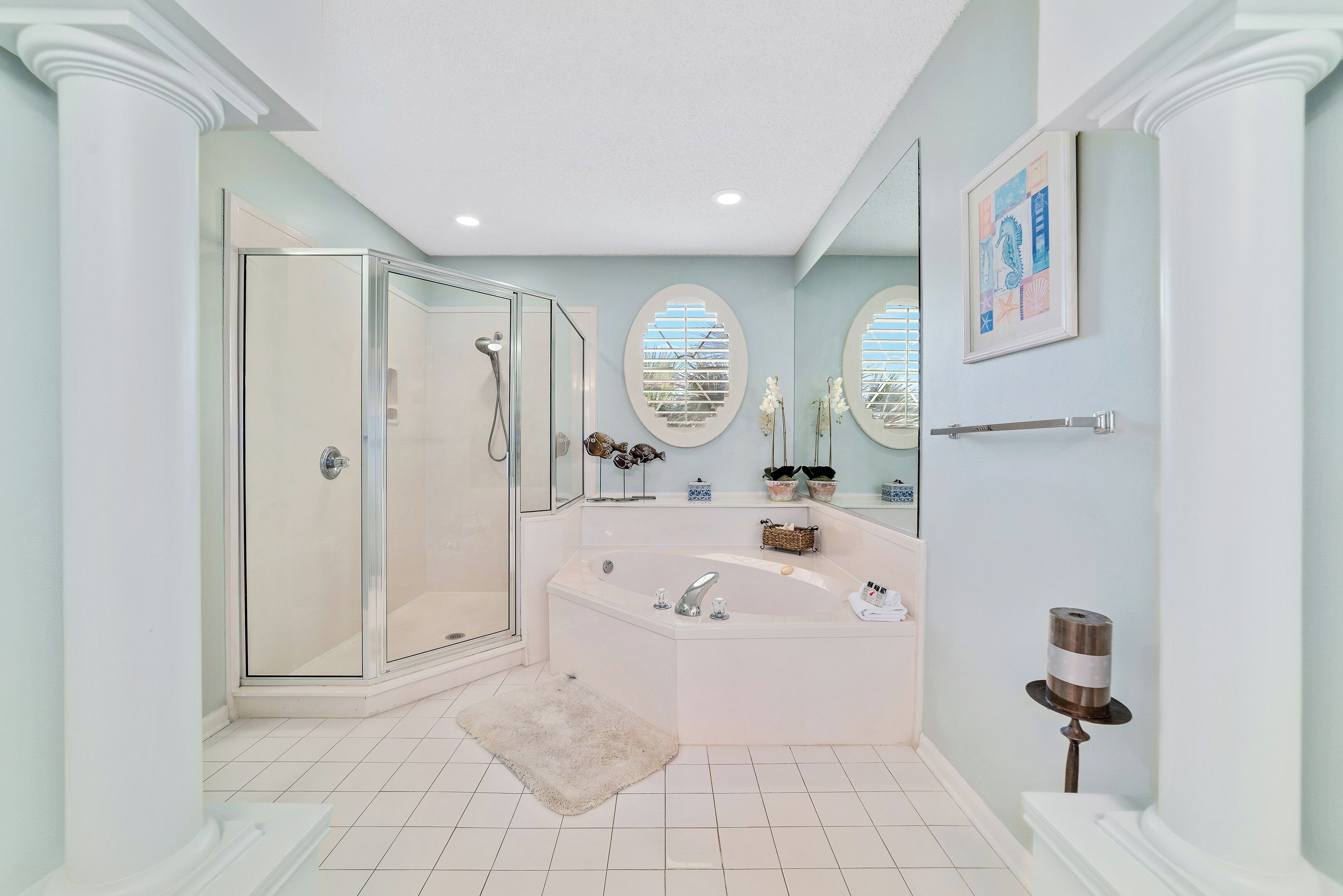 Un baño moderno con cabina de ducha de vidrio, bañera independiente y tocador con espejo.