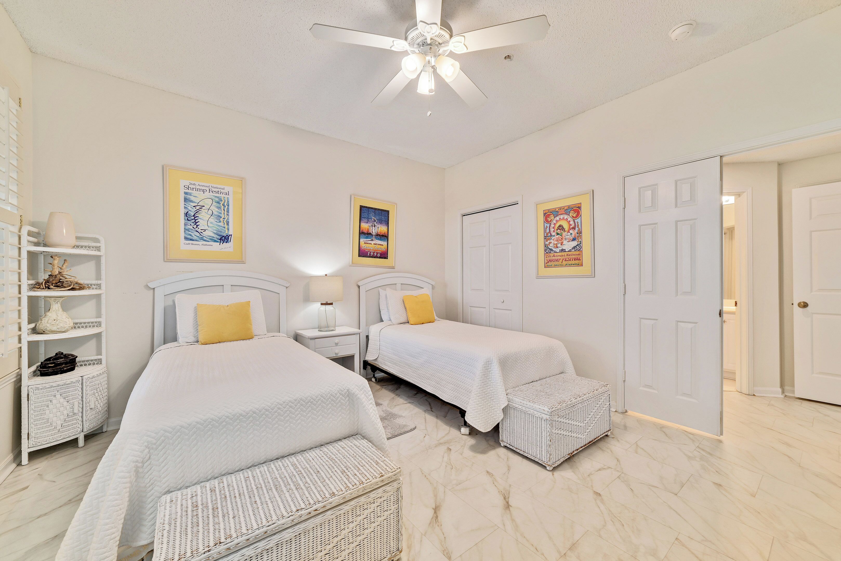 A bedroom with two beds, a ceiling fan, and a door leading to another room.