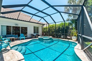 A covered swimming pool with a hot tub, outdoor seating, and a view of a house with a tiled roof. - Gated Community, Open Floor Plan, Private Screened Pool (Destin)