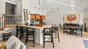 A spacious kitchen with a central island, wooden cabinets, and a dining area with chairs and a table. - Gated Community, Open Floor Plan, Private Screened Pool (Destin)