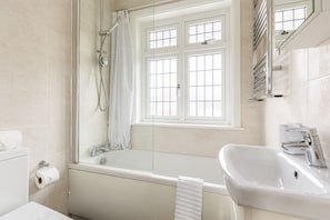 Ein Badezimmer mit Badewanne, Waschbecken, Toilette und einem Fenster mit Aussicht.