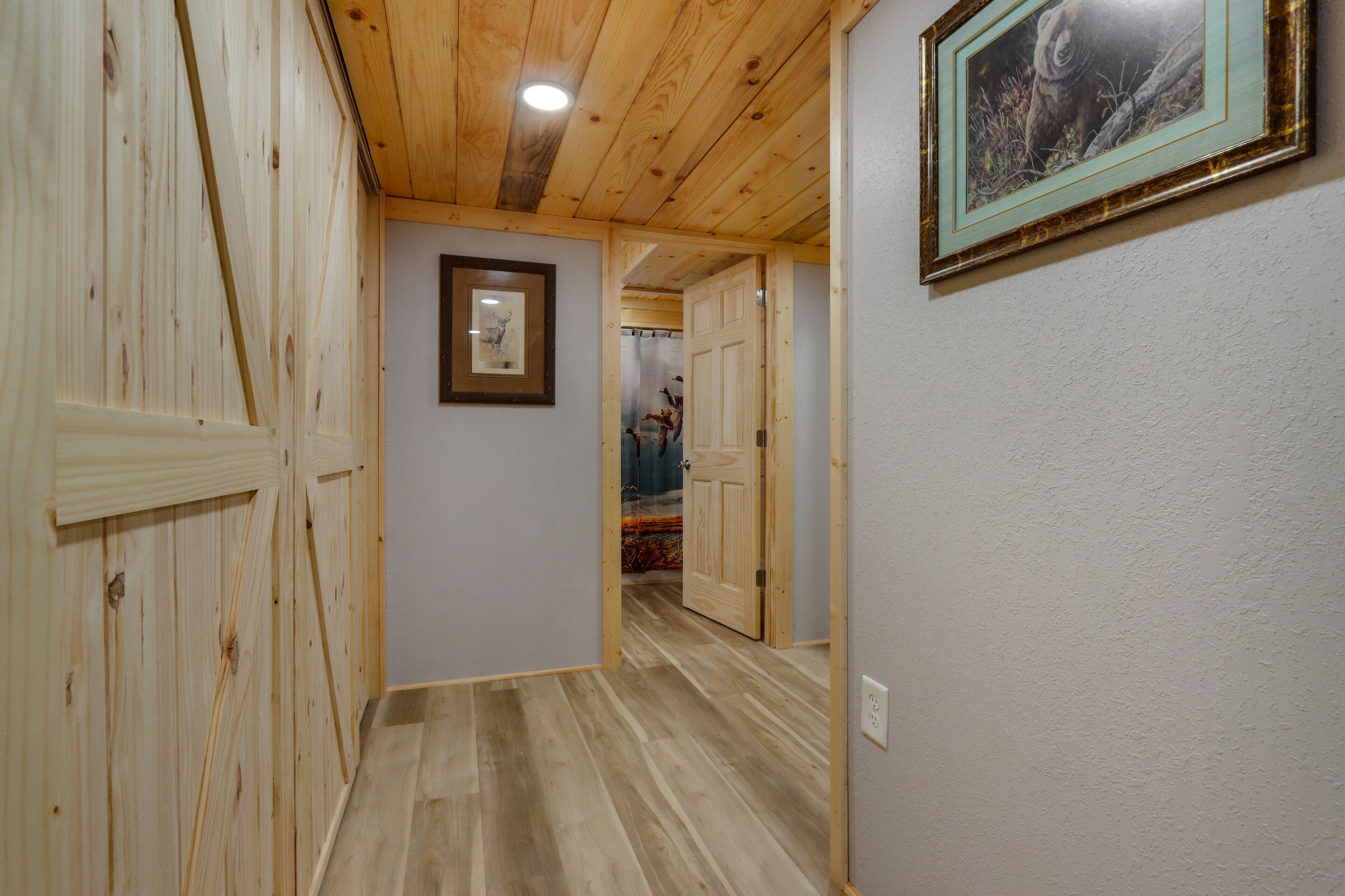 Un pasillo con paredes y techo de madera que conduce a una habitación con una puerta.