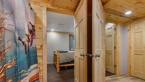 Un interior de madera con una cama, una puerta y una pared con cortina.