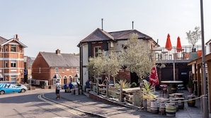 A street with a pub, outdoor seating, and a blue van parked on the side. - Andiamo (Poole)