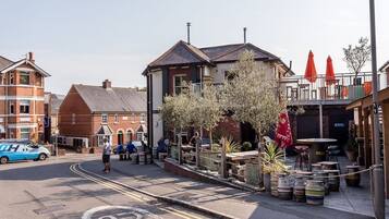 A street with a pub, outdoor seating, and a blue van parked on the side.