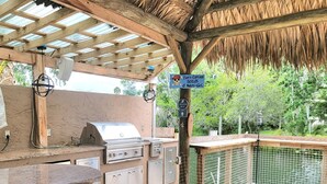 Zona cuina exterior amb una barbacoa, armaris i un senyal que indica una ruta d'evacuació.