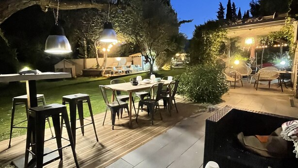 An outdoor patio area with a pool, dining table, chairs, and hanging lights. - PRETTY VILLA WITH POOL SLEEPS 8 (Tavel)