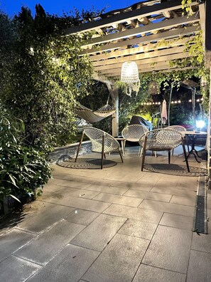 An outdoor patio with wicker furniture, a pergola, and string lights.