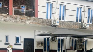 Un bâtiment à la façade blanche, doté d’une porte noire et d’un espace extérieur abrité aménagé en coin salon.