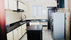 Une cuisine de taille réduite, équipée d’une cuisinière, d’un évier et d’un réfrigérateur.