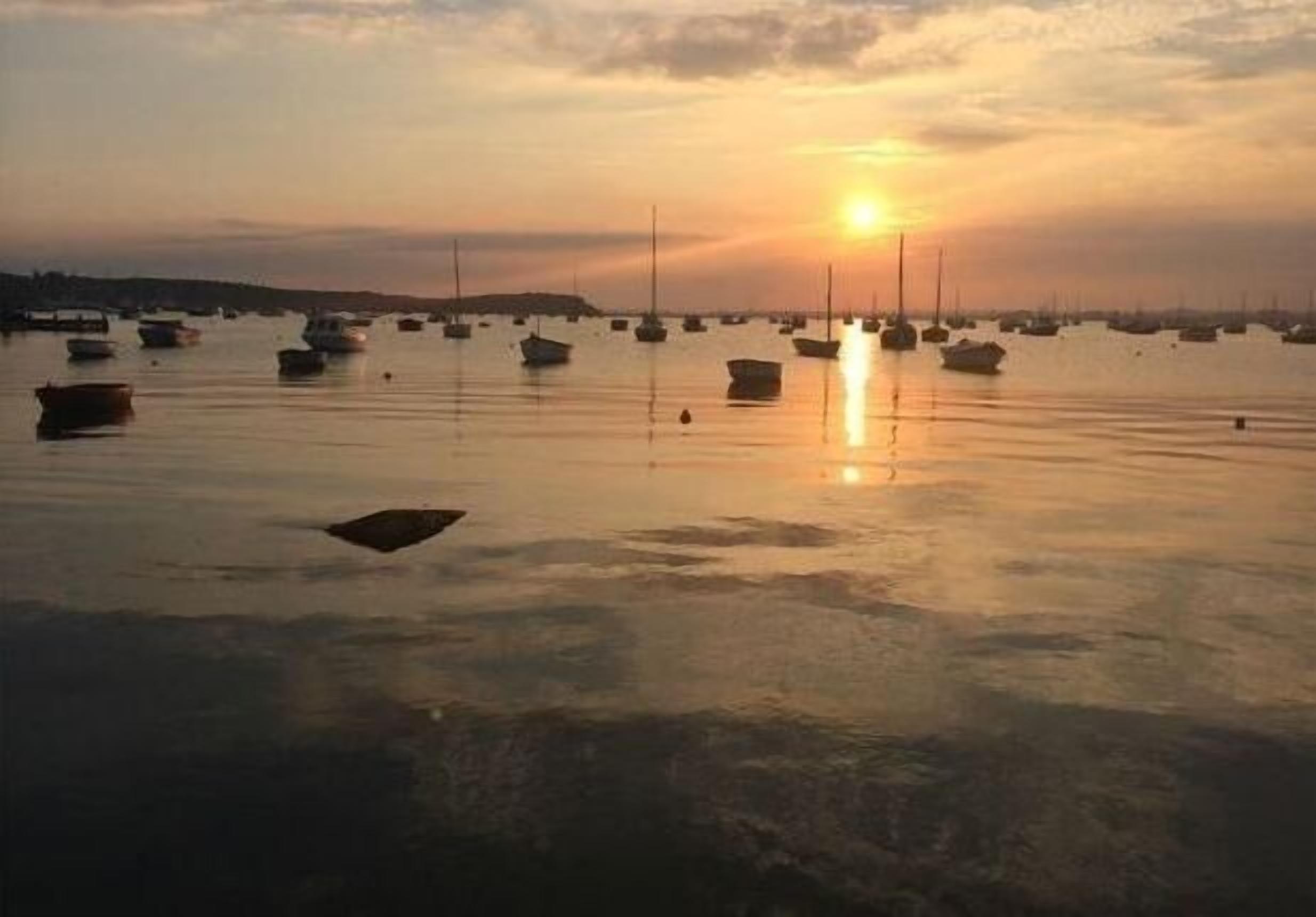 Ein ruhiger Hafen bei Sonnenuntergang mit darin verankerten Booten.