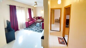 A living room with a sofa set, a coffee table, and a TV. - Apartment (fes)