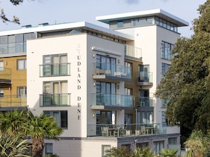 A modern multi-story building with balconies, large windows, and a sign reading 'STUDLAND DEN'. - Mussels (Bournemouth)
