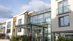 A modern building with a glass entrance and a sign reading "Sudland Dem".