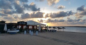 Restaurante à beira-mar com área externa, espaço coberto e vista para o mar.