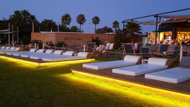 Un espace aménagé au bord de la piscine, avec des chaises longues et un bar.