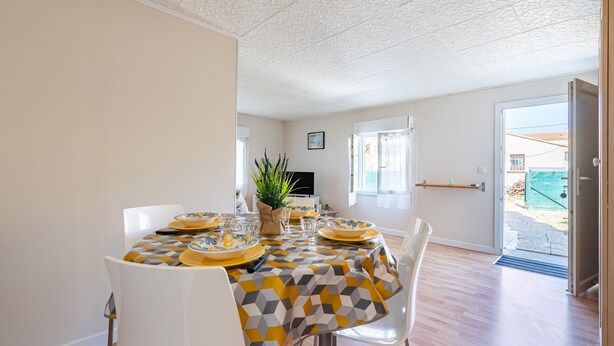 A dining area with a table set for four, a potted plant, and a view of the outside. - Le Quiloé - Apt lumineux proche mer (Frontignan)