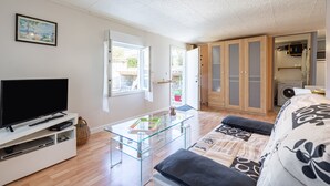 A modern living room with a flat-screen TV, glass coffee table, sofa, and wardrobe. - Le Quiloé - Apt lumineux proche mer (Frontignan)