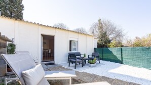 A patio area with outdoor furniture, a small table, and a door leading to an interior space. - Le Quiloé - Apt lumineux proche mer (Frontignan)