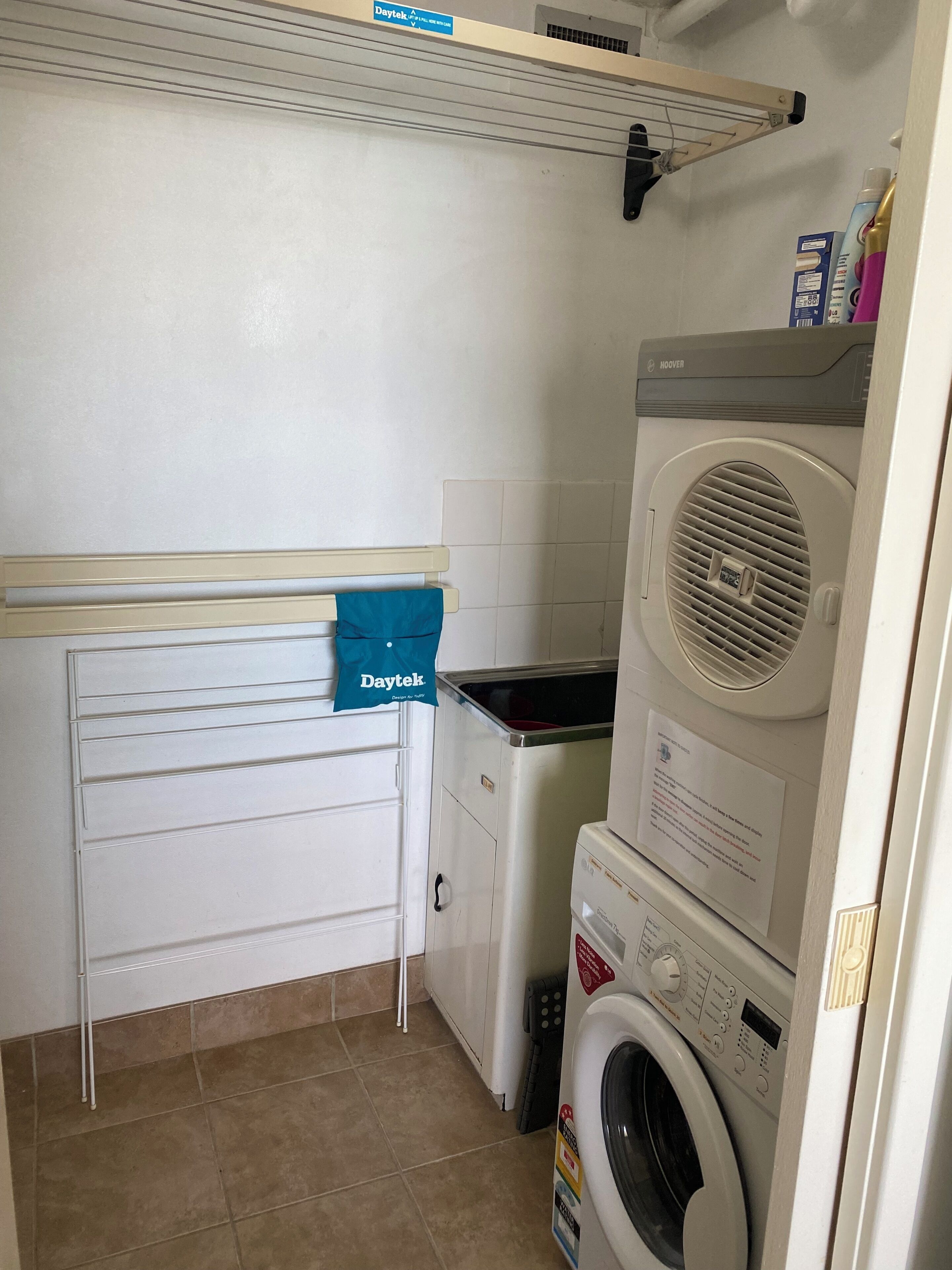 A laundry room with a dryer, washing machine, and a blue towel hanging on a rack.