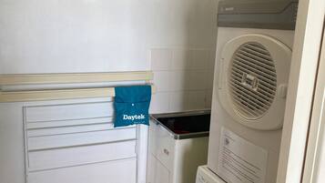 A laundry room with a dryer, washing machine, and a blue towel hanging on a rack.