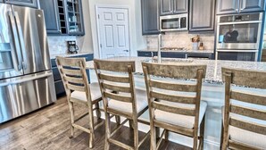 A kitchen with dark cabinets, stainless steel appliances, a wooden island with chairs, and a sign that reads 'BOARDWALK'.