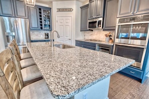 A kitchen with granite countertops, stainless steel appliances, and blue cabinetry.